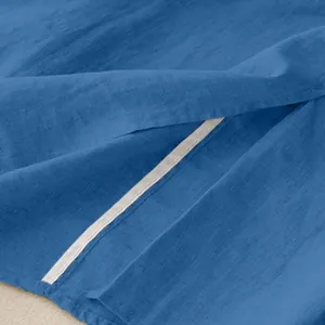 Close-up detail of blue solid color cotton linen skirt fabric and side slit hem design.