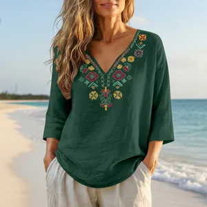 Detail of heavy floral embroidery on a dark green V-neck cotton linen summer top