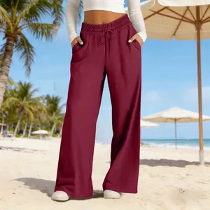Detailed view of wine red high-waisted wide-leg trousers on a sunny beach