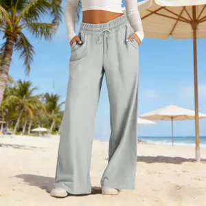 Detailed view of grey high-waisted wide-leg trousers for women on a beach setting