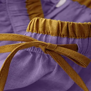 Macro detail of a retro linen skirt featuring purple fabric and a yellow drawstring waistband