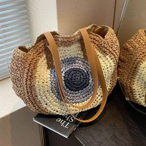 Detail of a woven straw shoulder bag with circular pattern and brown leather straps
