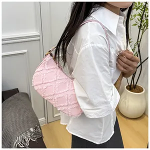 Detail of pink denim underarm bag with frayed diamond grid pattern on shoulder.