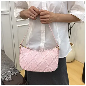 Detail view of stylish pink denim underarm bag with frayed diamond quilt pattern