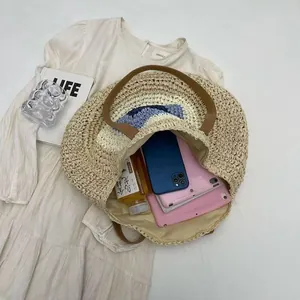 Detail view of round woven straw bag showing large capacity for essentials like tablets.