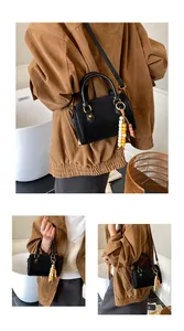 Nahaufnahme einer schwarzen Vintage-Boston-Tasche mit Goldakzenten und Perlenanhänger.
