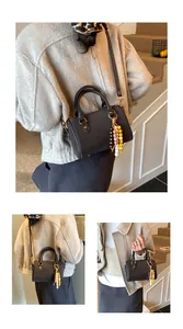 Detailansicht einer dunkelbraunen Vintage-Boston-Handtasche mit buntem Perlenanhänger