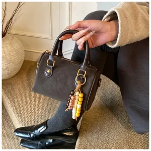 Detailansicht einer braunen Boston-Handtasche aus Wildleder mit bunten Holzperlen