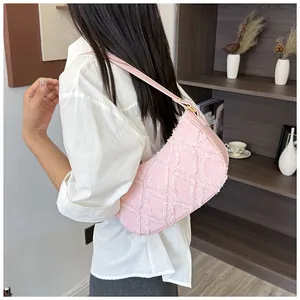 Chic pink denim underarm bag with frayed diamond quilt texture worn by a model