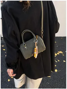 Dunkelgrüne Retro-Boston-Tasche mit Perlenquaste als Detailansicht über der Schulter