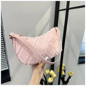 Detailed view of pink denim hobo bag with frayed diamond quilting and gold hardware