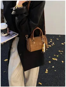 Nahaufnahme einer braunen Vintage-Boston-Handtasche mit dekorativem Perlen-Anhänger.