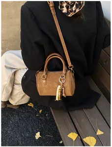 Nahaufnahme der braunen Wildleder Boston Bag mit Perlenanhänger und Schultergurt