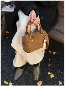 Nahaufnahme einer braunen Vintage-Boston-Handtasche mit Wildlederoptik und Perlenanhänger.
