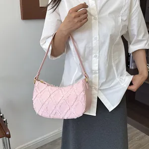 Fashionable pink denim underarm bag featuring a frayed diamond pattern and shoulder strap