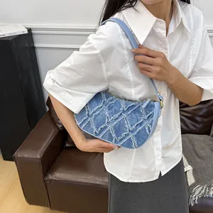 Trendy blue denim baguette bag with frayed diamond pattern and chic underarm style.