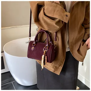 Detailansicht einer vintage burgunderroten Boston-Handtasche mit Perlen-Quasten-Anhänger