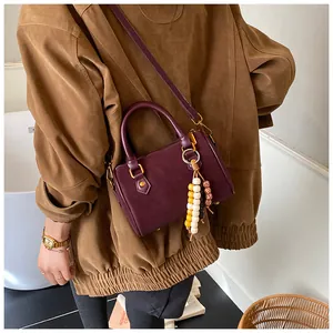 Klassische lila Boston-Umhängetasche kombiniert mit brauner Wildlederjacke für Retro-Look