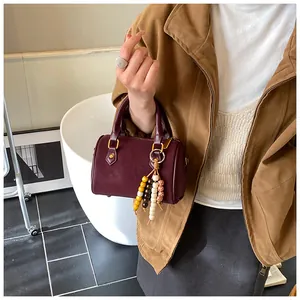 Detaillierte Ansicht einer klassischen weinroten Boston-Handtasche mit Perlenanhängern