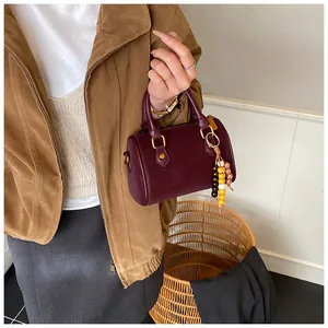 Detailansicht einer vintage burgunderroten Boston-Handtasche mit Perlenanhänger.