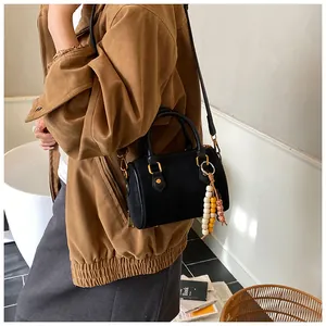 Nahaufnahme einer schwarzen Vintage-Boston-Handtasche mit bunten Holzperlen-Anhängern