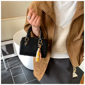 Elegante schwarze Boston-Handtasche mit bunten Perlenanhänger im modischen Retro-Stil.