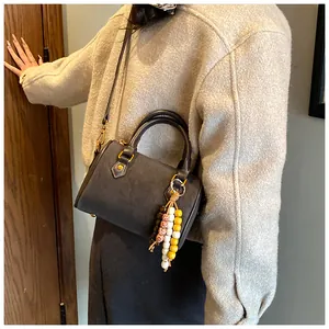 Klassische dunkelgraue Boston-Handtasche mit bunten Perlenquasten an einem Model
