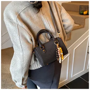 Detailansicht einer Vintage-Boston-Tasche mit Perlenanhänger und Gurt