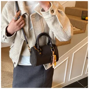 Detailansicht der braunen Retro-Boston-Handtasche mit elegantem bunten Perlenanhänger