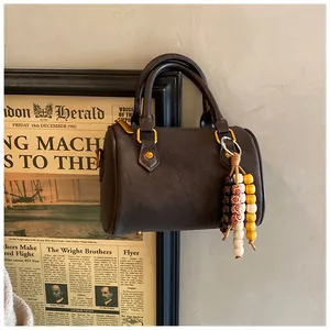 Detailansicht der braunen Boston-Handtasche mit farbenfrohem Perlenanhänger im Retro-Stil