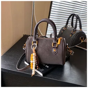 Detailansicht einer braunen Retro-Boston-Handtasche mit eleganten goldenen Beschlägen.