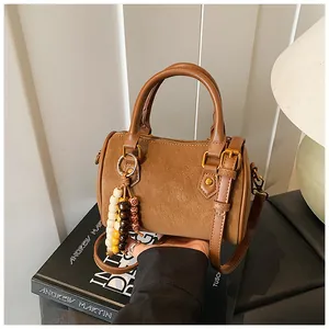 Detailansicht einer braunen Vintage-Boston-Handtasche mit dekorativem Perlenanhänger.