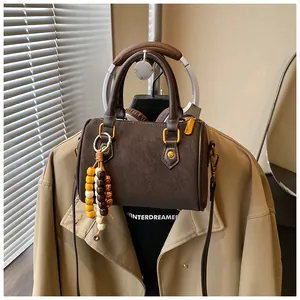 Retro-Boston-Handtasche in Braun mit Perlenanhänger und goldfarbenen Metallakzenten.