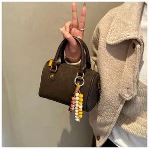 Nahaufnahme einer braunen Vintage-Boston-Tasche mit einem bunten Perlenanhänger-Accessoire