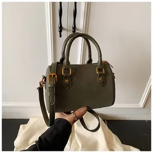 Detailansicht einer dunkelgrünen Vintage Boston Bag mit goldenen Beschlägen in der Hand.
