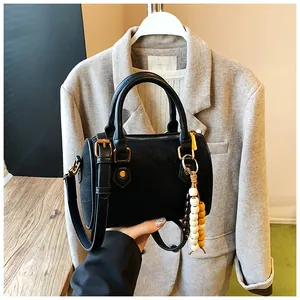 Nahaufnahme einer schwarzen Boston-Tasche mit glatter Textur und dekorativem Perlenanhänger.