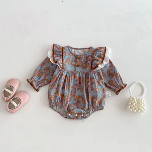 Baby floral long sleeve romper detailed view with ruffles and cute pearl bag prop.