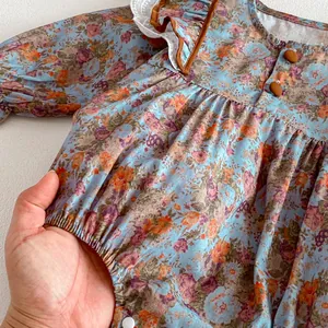 Cute infant long sleeve floral print baby romper with lace collar and button detail.
