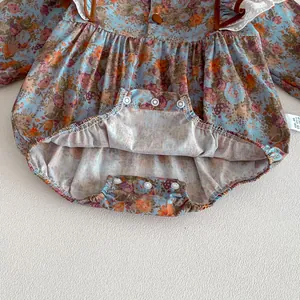 Infant floral print long sleeve romper detail close-up showing snap buttons and ruffles.