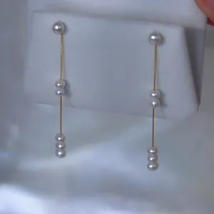 Elegante lange Quastenohrringe mit natürlichen weißen Perlen an goldenen Ketten