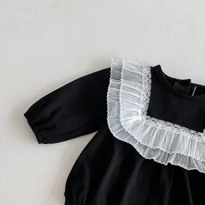 Close-up detail of infant baby girl black long sleeve romper with white lace ruffle collar.