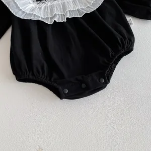 Baby black romper detail featuring white lace collar, long sleeves and soft cotton fabric.