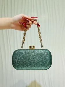 Elegante pochette da sera glitterata verde con catena dorata tenuta in mano