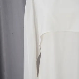 Close-up van het delicate witte chiffon cape-detail op deze elegante avondjurk voor dames