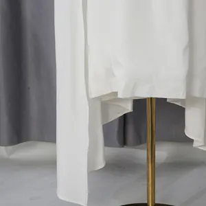 Gedetailleerd overzicht van de zoom en stof van een witte avondjurk op een pop