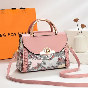 Detalle del bolso rosa con estampado de cachemira y elegante asa de metal dorado