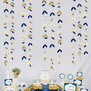 Detailed view of hanging paper leaf garlands in blue and gold for party backdrop decoration.