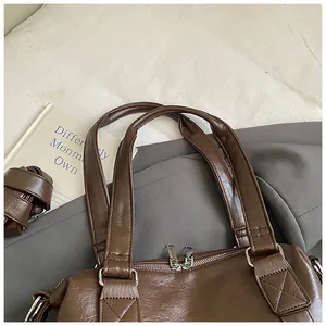 Vue détaillée de la poignée du sac Boston en cuir marron et fermeture éclair, style rétro.
