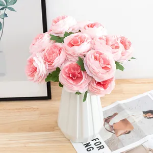 Artificial pink peony flower bouquet in white ceramic vase for home decoration setup today.
