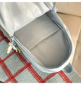 Detail view of a cute light blue school backpack interior lining with compartments and sweet pendant.